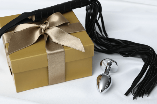 An anal plug, flogger, and gift box